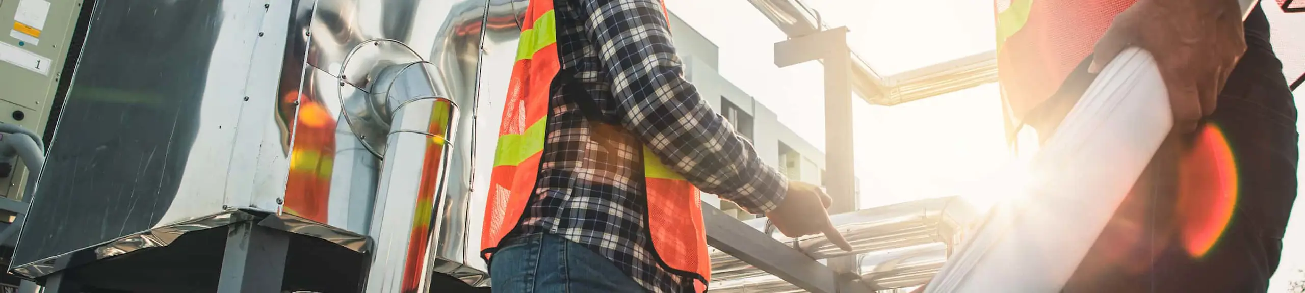 Two men examining air conditioning unit and plans Two men examining air conditioning unit and plans